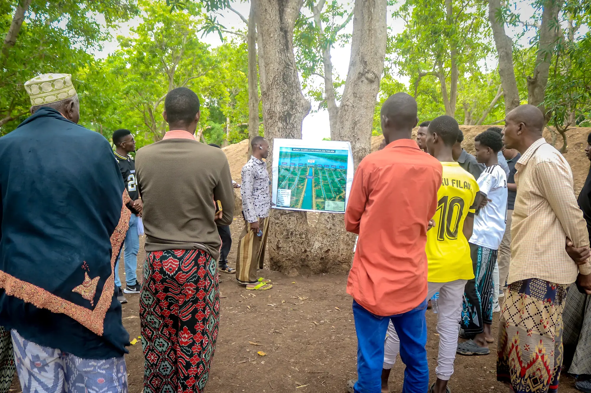 Participants standing in a loose ring around a map board held up on open ground.